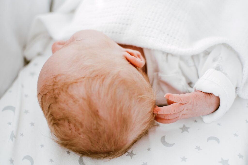 Baby with head turned left on back